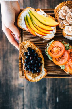Lezzetli sağlıklı tostlar kahvaltı, öğle yemeği ya da atıştırmalıklar ellerinde tahta bir tahtanın üzerinde..