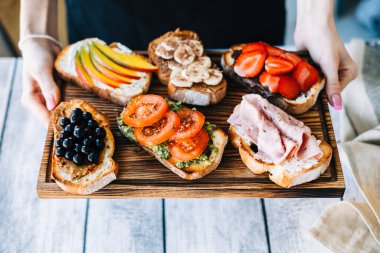 Lezzetli sağlıklı tostlar kahvaltı, öğle yemeği ya da atıştırmalıklar ellerinde tahta bir tahtanın üzerinde..