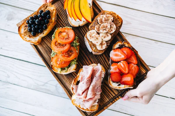 Lezzetli sağlıklı tostlar kahvaltı, öğle yemeği ya da atıştırmalıklar ellerinde tahta bir tahtanın üzerinde..