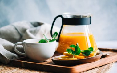 Çaydanlıkta demlenmiş deniz dikenli çay, portakallı, cam bardaklı taze portakal, nane ve bal..