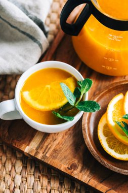 Çaydanlıkta demlenmiş deniz dikenli çay, portakallı, cam bardaklı taze portakal, nane ve bal..