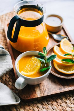 Çaydanlıkta demlenmiş deniz dikenli çay, portakallı, cam bardaklı taze portakal, nane ve bal..