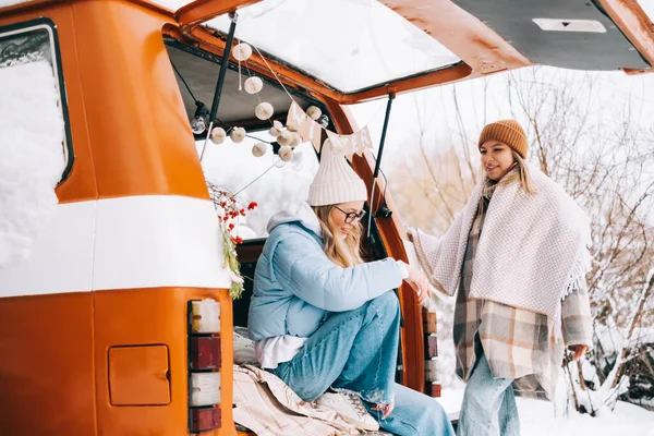 两个快乐的女性朋友坐在冬季营房的面包车里享受假期的画像 — 图库照片