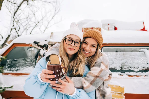 两个快乐的女性朋友站在面包车旁享受冬天的形象 — 图库照片