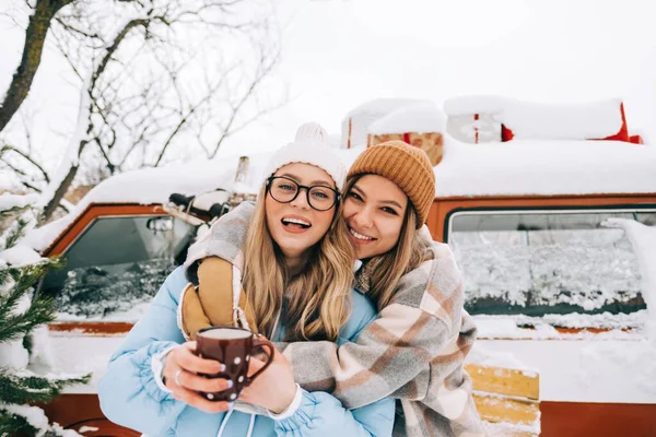 两个快乐的女性朋友站在面包车旁享受冬天的形象 — 图库照片