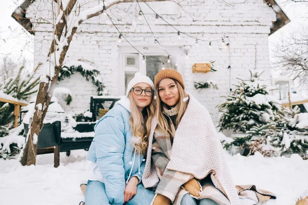 两个快乐的女性朋友在下雪时坐在后院的肖像 享受着冬天的时光 — 图库照片