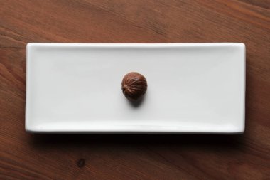 Ahşap bir masada uzun bir tabakla izole edilmiş közlenmiş bir chesnut resmi.