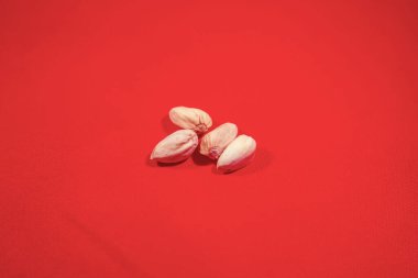 Açılmamış dört büyük fıstıklı parlak kırmızı kumaş arka planda.