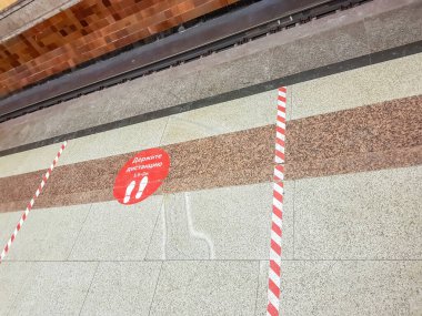 Moskova, Rusya - 10 Aralık 2021: mesafeyi koruyun. Krasnoselskaya metro istasyonunun mermer zemininde kırmızı uyarı etiketi. Rusça yazı