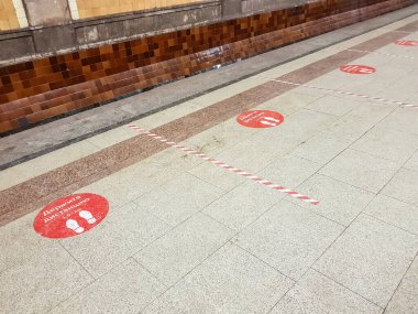 Moskova, Rusya - 10 Aralık 2021: mesafeyi koruyun. Krasnoselskaya metro istasyonunun mermer zemininde kırmızı uyarı etiketi. Rusça yazı
