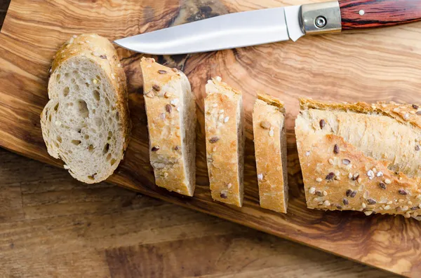 Pane con semi su tavola di legno e coltello — Foto Stock