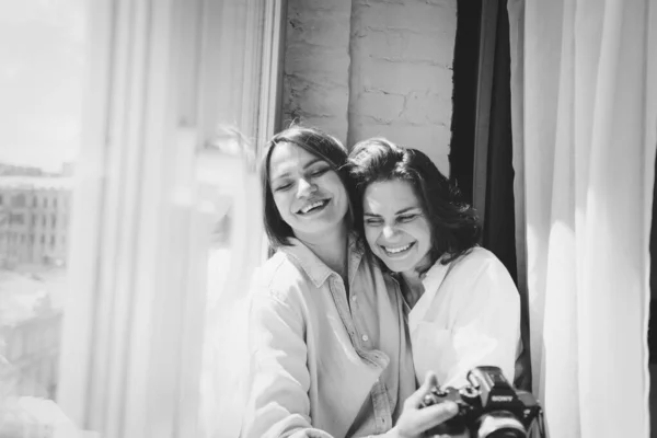 To unge kvinner som ler og er lykkelige. De klemmer og tar selfies. – stockfoto