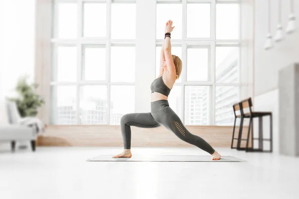 An adult woman practices Ashtanga Vinyasa yoga at home. — Stock Photo, Image