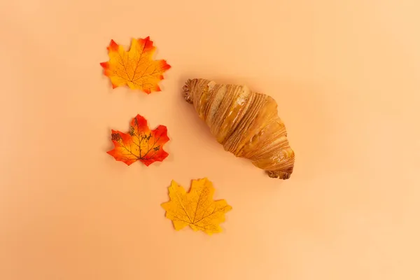 Croissant met herfstbladeren op oranje achtergrond — Stockfoto