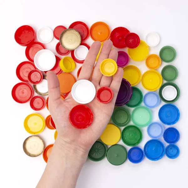 rainbow color plastic bottle cap in hand, , remove cap before recycling, concept of environmental pollution, eco friendly behavior