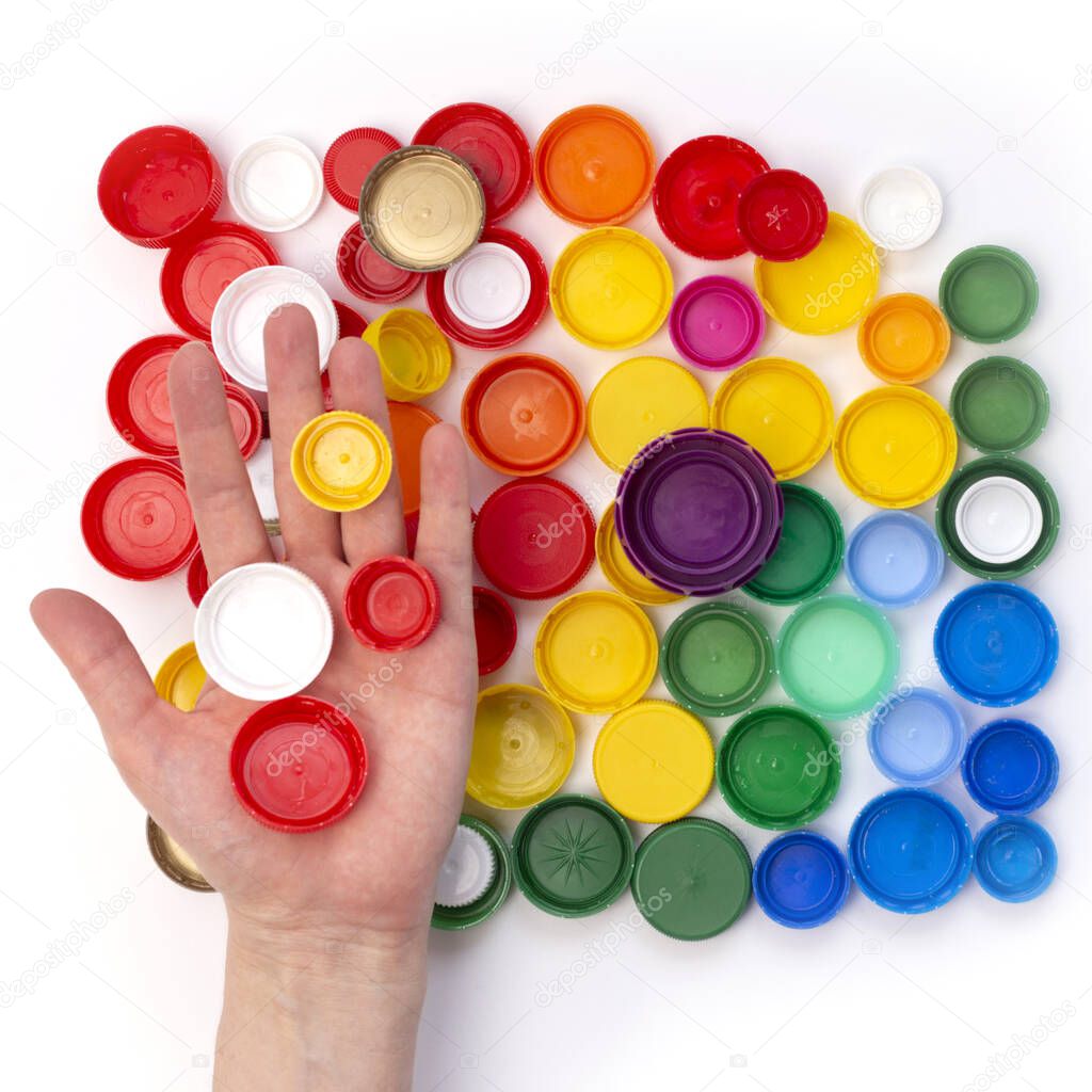 hand holds plastic bottle lid, rainbow color pattern, remove cap before recycling, concept of environmental pollution, eco friendly behavior