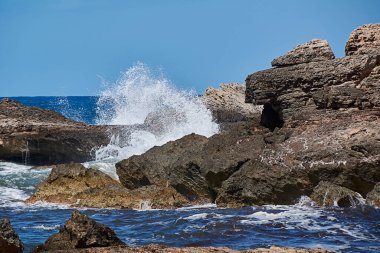 Kıyıdaki kayalar dalgaların vurduğu yer. Balear Adaları, Akdeniz, mavi gökyüzü, su damlaları.