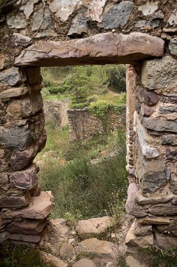 Jinquer, Castellon, İspanya. Bitkinin ortasında terk edilmiş bir köyün yıkıntıları içinde evler. Dağ, bir grup ev. Yollar, İspanya İç Savaşı