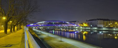 Peder Bernatek yaya köprüsü, geceleri Krakow, Vistula nehri, Courland Bulvarı, suda yansıma, derin mavi..