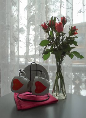 Bir buket gül ve masada kırmızı kalpler olan bardaklar. Yüksek kalite fotoğraf