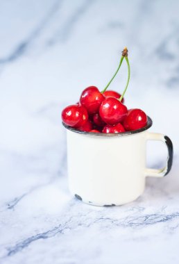 Seramik masadaki metal bardakta yeni toplanmış kirazlar.