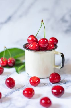 Seramik masadaki metal bardakta yeni toplanmış kirazlar.