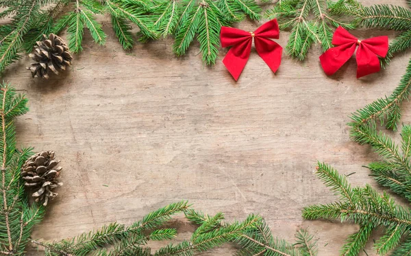 Frame from pine branches and christmas decoration with copy space on wooden background.