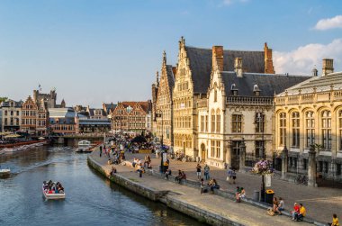 GHENT, BELGIUM - 20 AĞUSTOS 2013: Şehir manzarası, insanlar Ghent, Belçika 'nın tarihi şehir merkezinde bir rıhtım olan Graslei' de güzel bir yaz öğleden sonranın tadını çıkarıyorlar. Ortaçağ limanının bir kısmı şu anda şehrin kültürel ve turistik merkezidir.