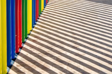 Renkli bir çit ve gölgesi görünüyor.