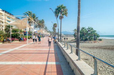 ESTEPONA, İspanya - 12 Ekim 2021: Güney İspanya 'nın Malaga eyaleti Costa del Sol' da bir kasaba olan Estepona 'nın kıyı şeridinde gezinen insanlar