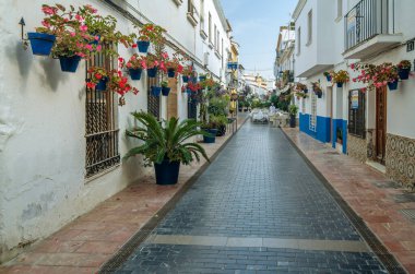 ESTEPONA, İspanya - 12 Ekim 2021: Estepona 'nın merkezinde dar sokaklar, tipik Endülüs kasabası, Costa del Sol, güney İspanya' da bulunan renkli saksılarla süslenmiş beyaz evler
