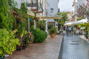 ESTEPONA, İspanya - 12 Ekim 2021: Estepona 'nın merkezinde dar sokaklar, tipik Endülüs kasabası, Costa del Sol, güney İspanya' da bulunan renkli saksılarla süslenmiş beyaz evler