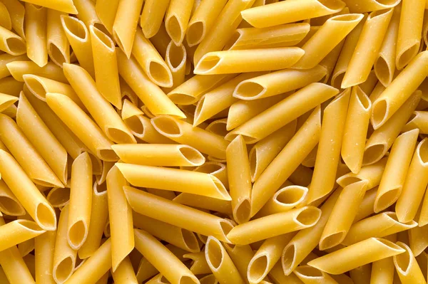 Pile of Penne Pasta Noodles Background Close Up.