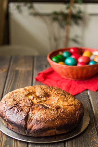 Kozunak (Traditional Easter sweet bulgarian bread) and colored eggs in a red wicker basket on a table of wooden planks