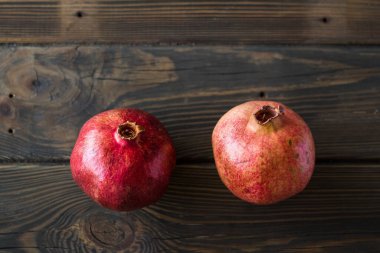 Tahta bir masada iki kırmızı nar.