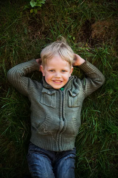 Томбой лежит на траве и улыбается. — стоковое фото