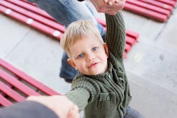 En vacker liten pojke tittar upp på sina föräldrar, hand i hand — Stockfoto