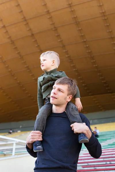 Pequeño niño sentado en los hombros de padre — Foto de Stock