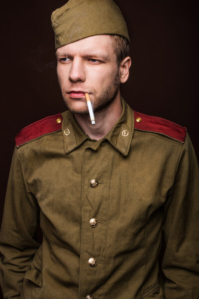 Second world war russian soldier smoking cigarette and looks at something