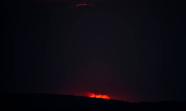 Güneş alacakaranlıkta ufukta batıyor. Yoğun renklerden oluşan dramatik bir gökyüzü.