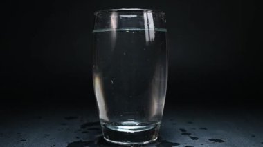 a glass of water on a black background is illuminated by light on a black background