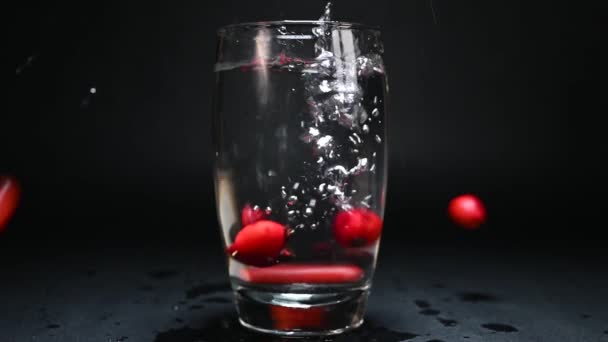 Rose Hips Falling Glass Water Black Background Illuminated Light — Stock Video