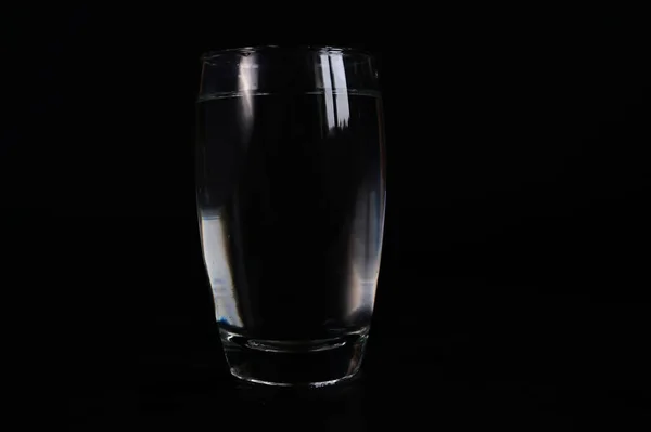 a glass of water on a black background, dark