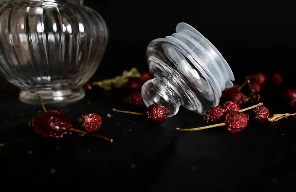 a glass lid from a decorative dish lies on a black background with rose hips