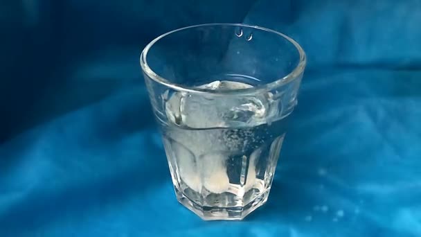 Tabletka musująca rozpuszcza się w szklance wody. — Wideo stockowe