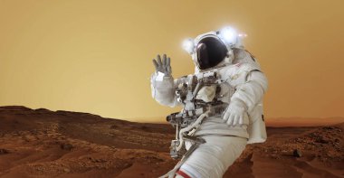 Uzay giysisi içindeki astronot ve ışıklı bir kask Mars 'ın kırmızı gezegeninde duruyor ve elini sallıyor. Mars konseptine hoş geldiniz. Uzay adamı seyahat eder