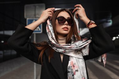 Havalı güneş gözlüklü, seksi dudakları olan şık Avrupalı genç bir kadın şehirde zarif ipek bir fular takıyor. Portre işi manken kız. Sokaktaki klasik güzellik kraliçesi..