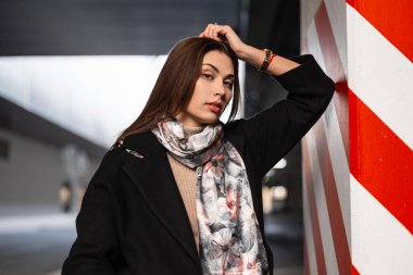 Temiz, sağlıklı tenli, seksi dudaklı, zarif elbiseli, kahverengi saçlı hoş, modaya uygun, genç bir bayan kapalı alanda kırmızı-beyaz çizginin yanında dinleniyor. Çekici kız model. Bayan..