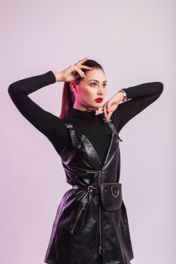 Moda mankeni şık gömlekli, şık, siyah kısa elbiseli, modern bir duvarın yanında seksi kırmızı dudaklı şık bir kadın. Muhteşem güzel kız esmer odada duruyor..