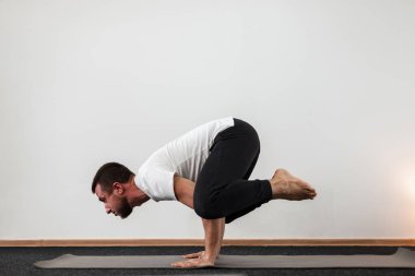 Atletik genç adam amuda kalkıyor ve dengesini koruyor. Profesyonel adam spor salonunda yoga yapıyor..